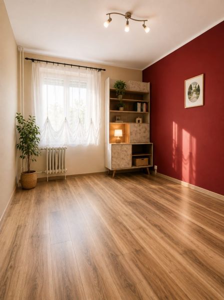 A room in a 3-room apartment with a wooden decor floor, a red wall, and a shelving cabinet.