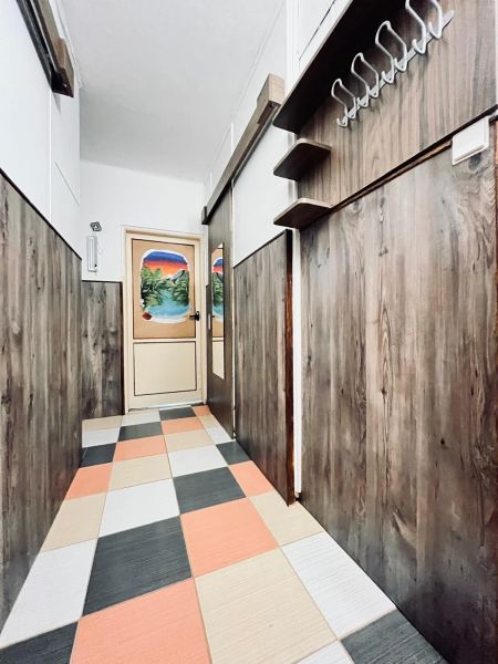 A hallway in a 3-room apartment with colorful tiles and wooden decor on the walls.
