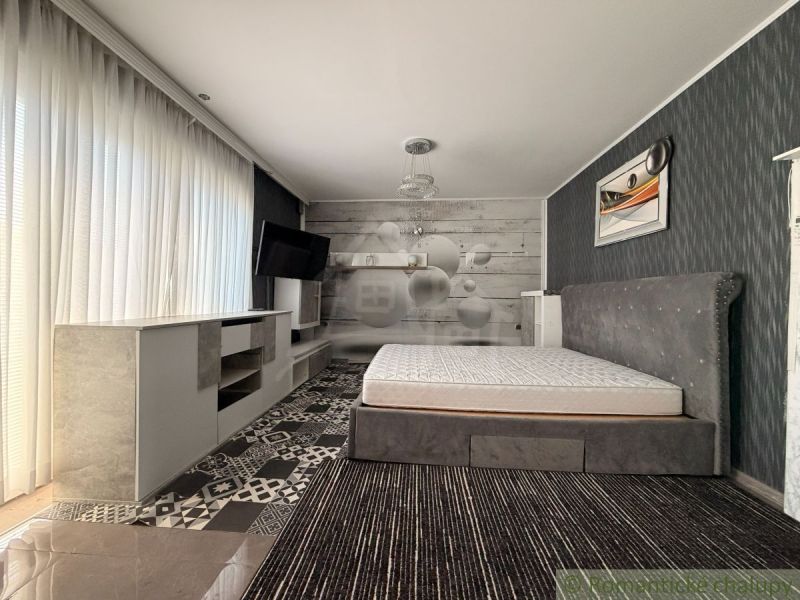 The bedroom with a bed in the family house has a stylish wallpaper and a TV on the wall.