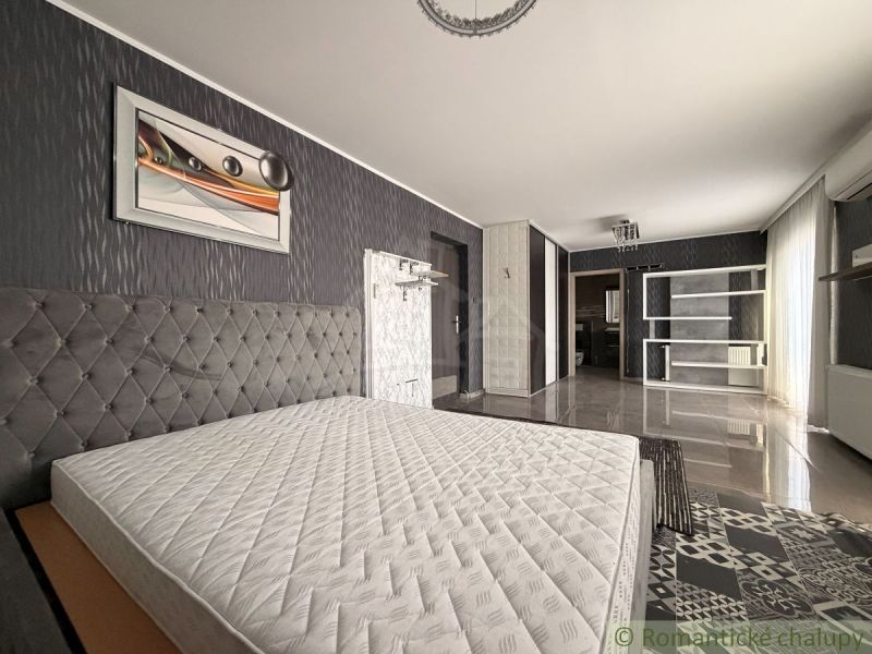 A bedroom in a family house with a striking wallpaper and a bed without a mattress.