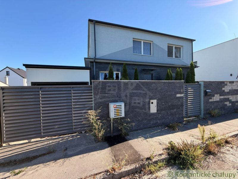A family house in Komárno with a modern fence and landscaping with plants at the entrance.