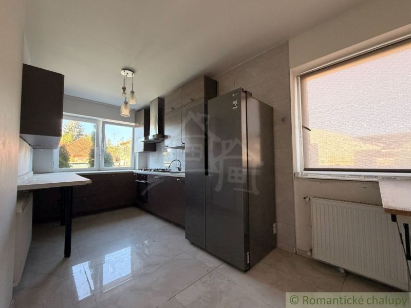 A kitchen in a family house with light walls and dark furniture.