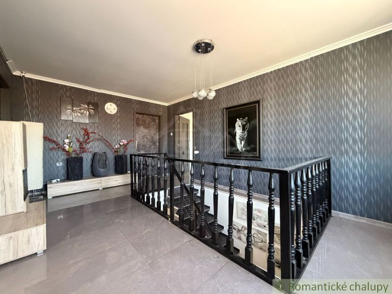 The interior of a family house with dark gray walls, decorative decorations, and a staircase.
