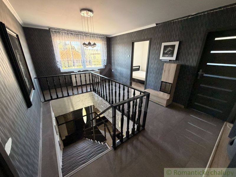 A staircase with black railings in a family house, with a view from the window.