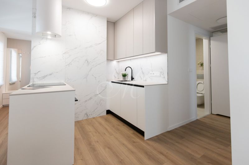 A kitchen in a 2-room apartment with a wooden decor floor and marble details.