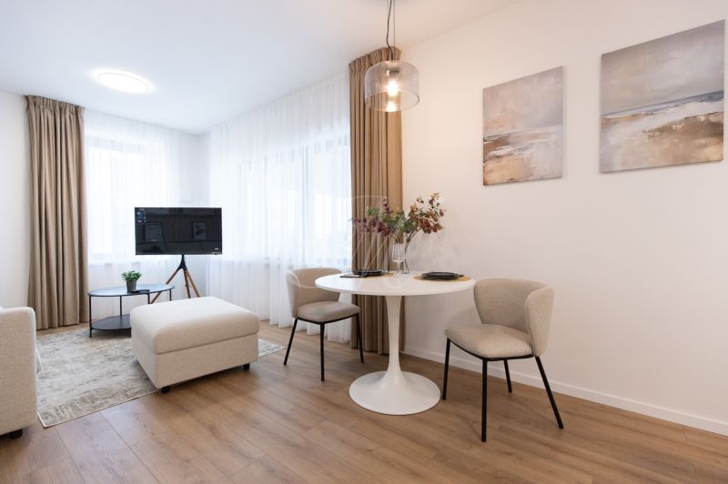Living room of a two-room apartment with a wooden decor floor, table, chairs, TV.