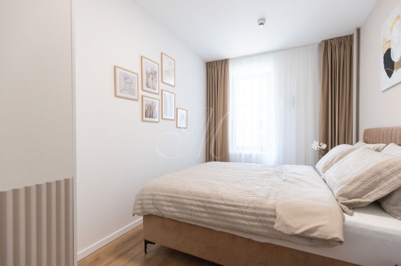 A bright bedroom with a bed, paintings, and a wooden decor floor in a two-room apartment.