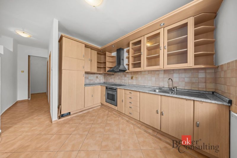 A kitchen with wooden decor, built-in appliances, and tiles in a 2-room apartment.