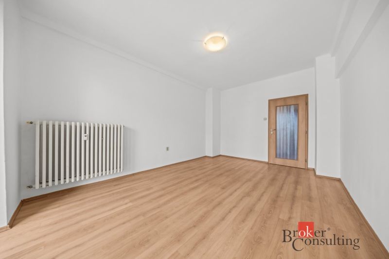 A room with a wooden floor decor and white walls in a 2-room apartment.