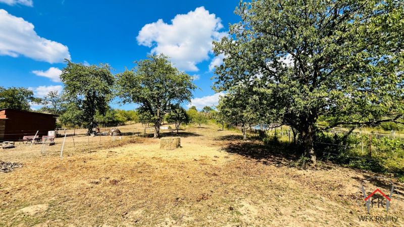 A plot of land by a family house in Ondavské Matiašovce with grass and trees in the countryside.