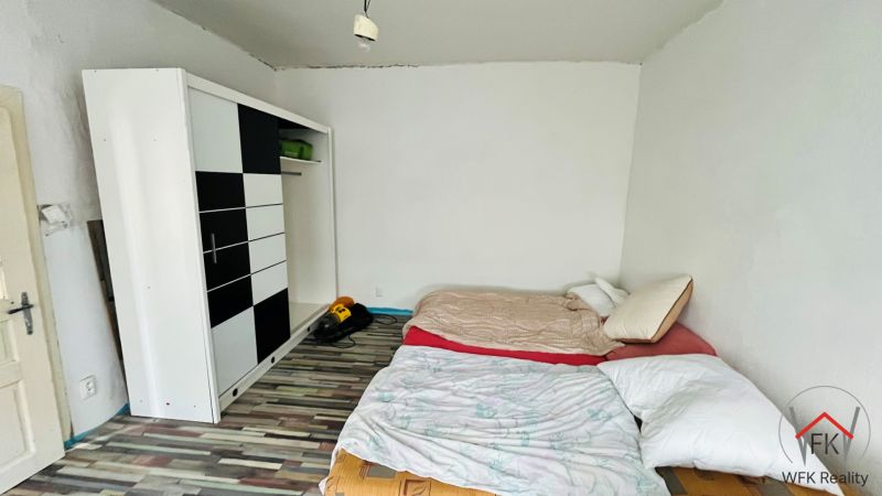Bedroom with a bed, wardrobe, and wooden decor flooring in a family house.