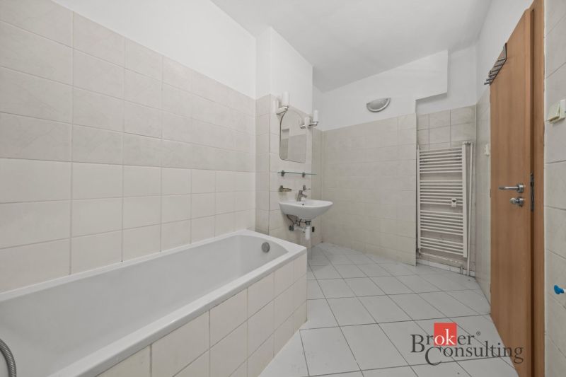 A bathroom with a bathtub, sink, and radiator in a 2-room apartment.