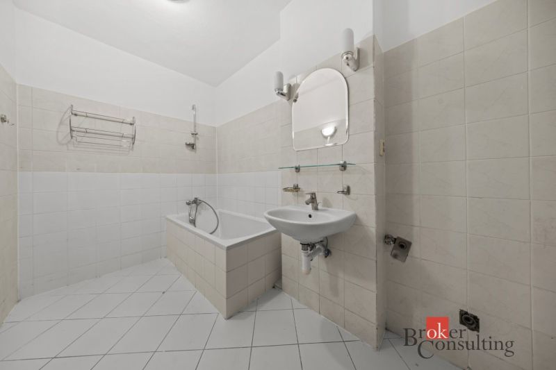 Bathroom with a bathtub and a sink in a 2-room apartment, light tiles.