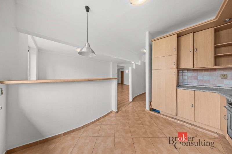 A kitchen in a 2-room apartment with light tiles and wooden decor cabinets.