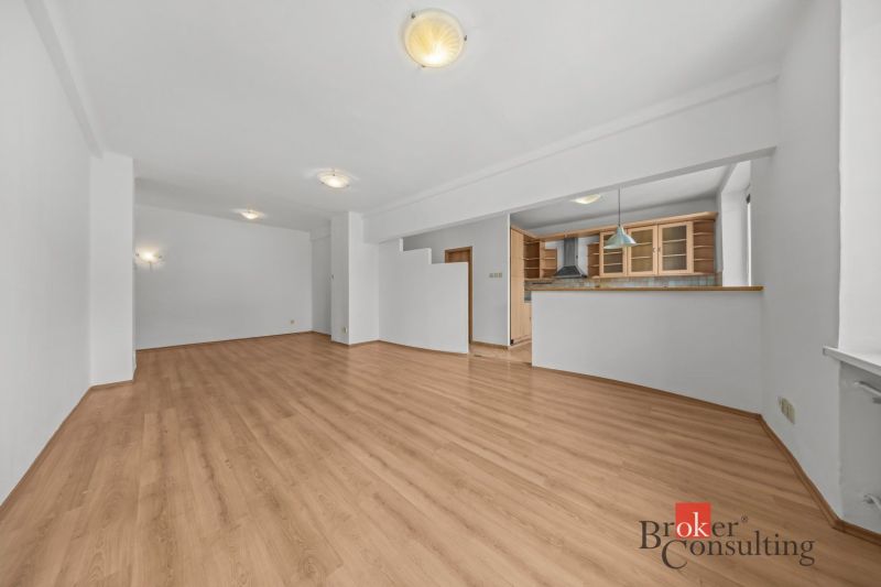 A spacious living area with a kitchenette and a wooden decor floor in a 2-room apartment.