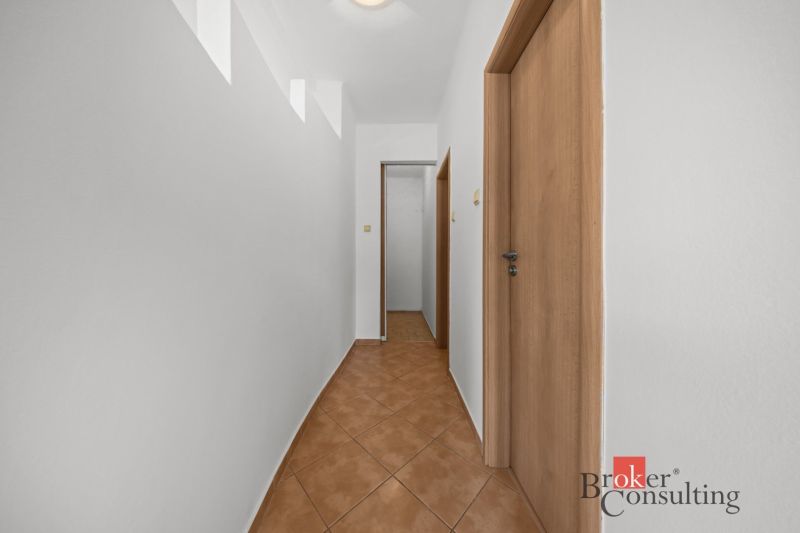 A hallway with light walls and tiles in a 2-room apartment.