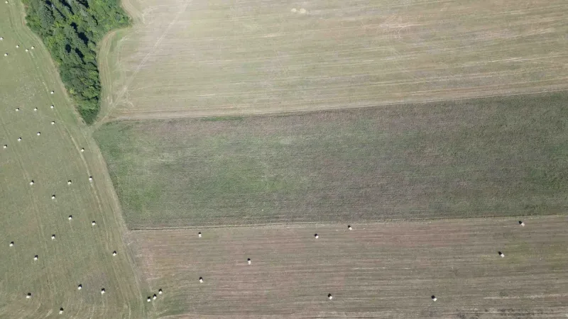 Aerial view of agricultural and forest lands in Plaveč with hay bales.