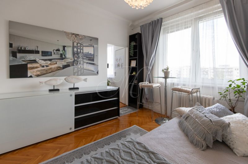 A bright room with wood-decor flooring, a sofa, and decorative elements in a 2-room apartment.