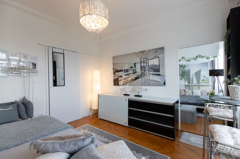 Bedroom with wood-patterned flooring, a bed, and modern lighting in a 2-room apartment.