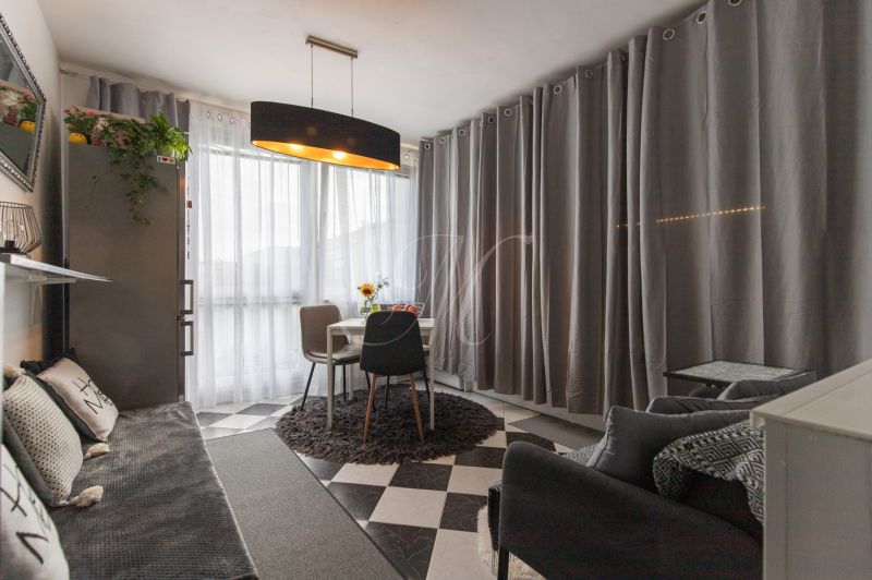 Living room in a two-room apartment with a dining table and gray curtains.