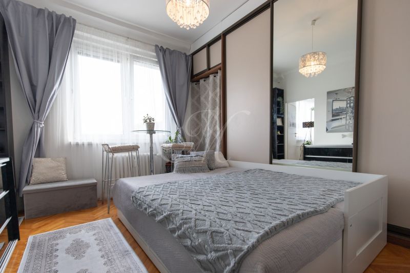 Bedroom in a 2-room apartment with a bed, mirrored wardrobe, and floor with wood decor.