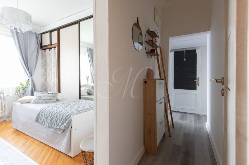 Two-room apartment with a bed, wardrobe, mirrors, and a floor with a wooden decor.