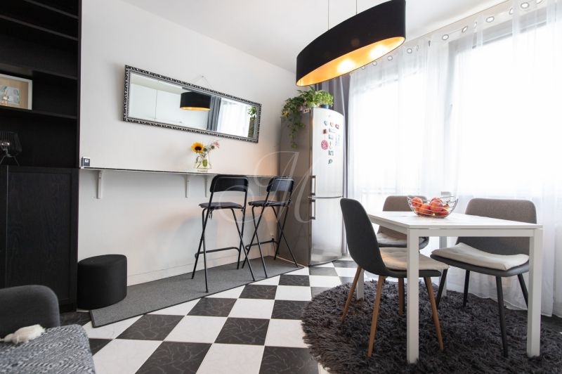 Dining area in a 2-room apartment with a dining table and black chairs.