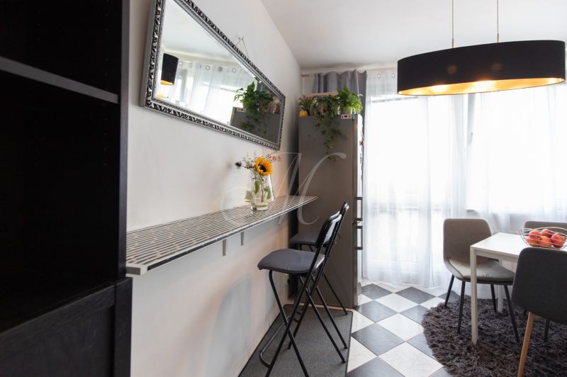 A kitchen with a dining table, a mirror, and high chairs in a 2-room apartment.