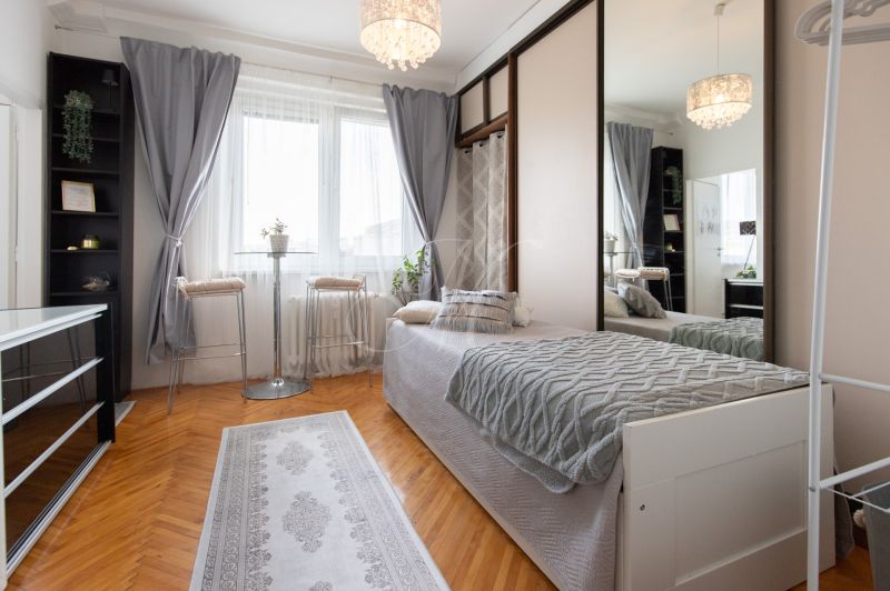 A room in a 2-room apartment with a bed, a mirrored wardrobe, and a floor with a wooden decor.
