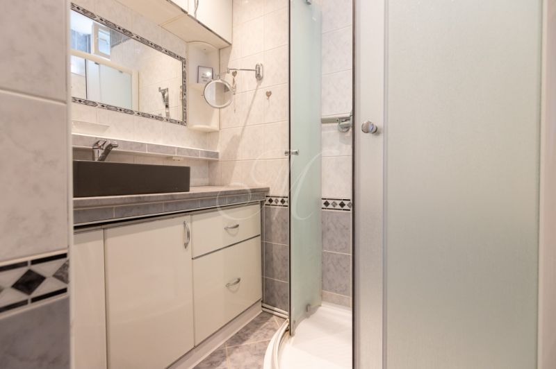 Bathroom with a glass shower enclosure and a mirror in a 2-room apartment.