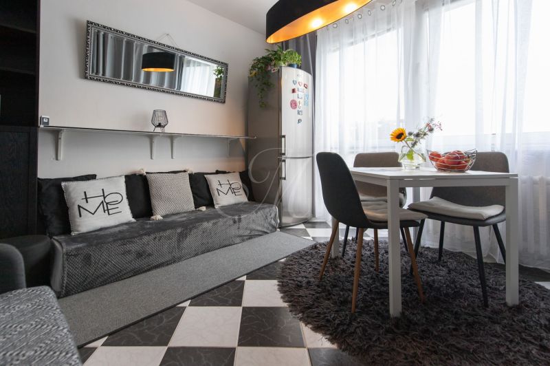 Living room with simple furniture, a mirror, a dining table, and a carpet.
