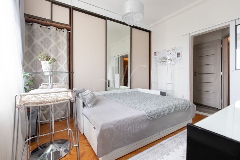 Bright room with a bed, wardrobe with mirrored doors, and a wooden decor floor.