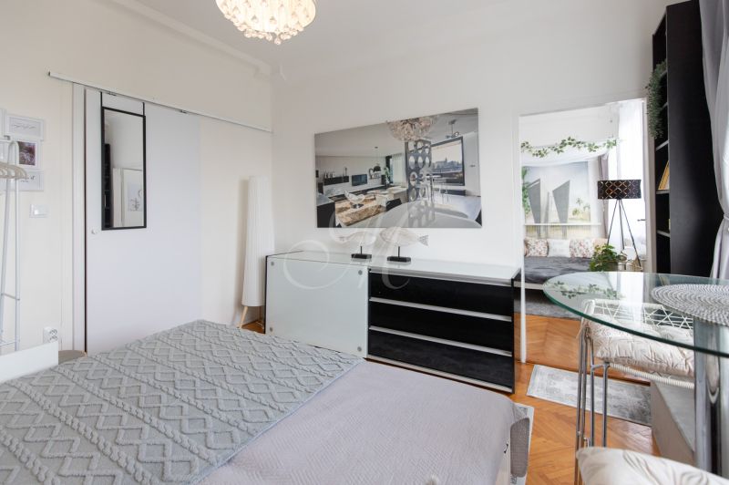A bedroom in a two-room apartment with a wooden decor floor and elegant furniture.