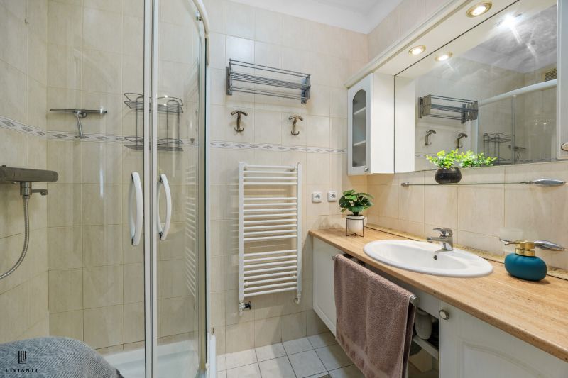 Bathroom with a spacious shower, sink, and light tiles in a 2-room apartment.