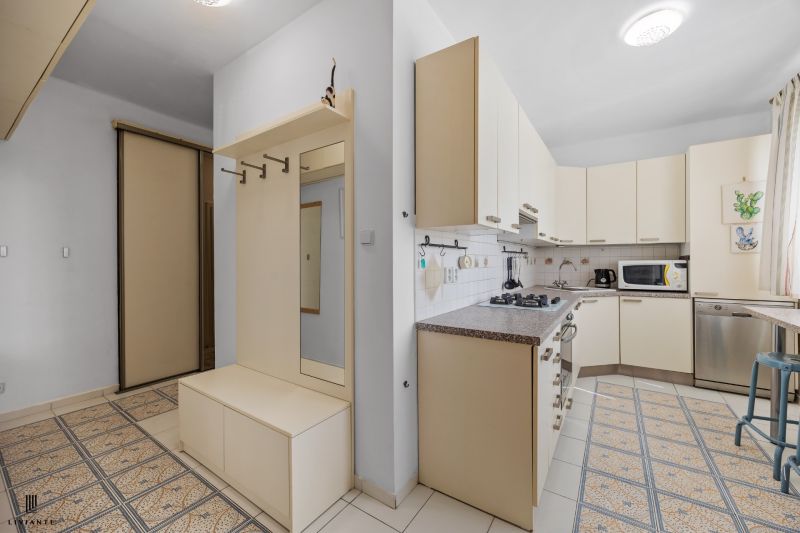 A kitchen in a 2-room apartment with white cabinets and built-in appliances.