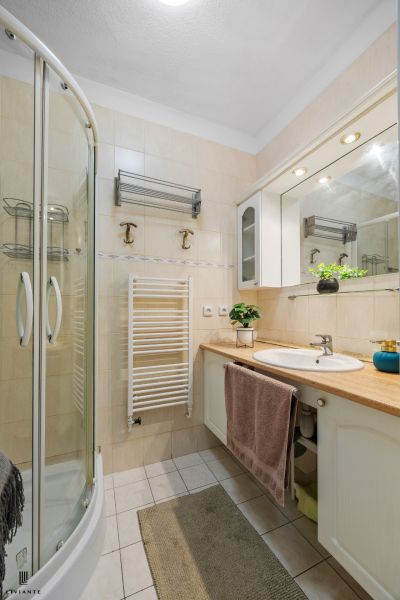 Bathroom with a shower, sink, cabinets, and floral decoration in a 2-room apartment.