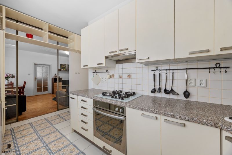A kitchen in a 2-room apartment with a gas stove, a mirrored wardrobe, and tiles.