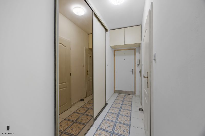 A hallway in a 2-room apartment with tiles and a built-in wardrobe.