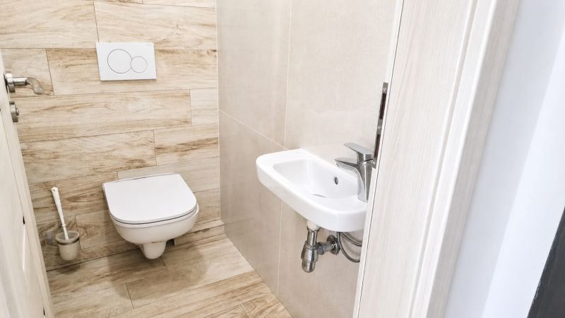 Bathroom with toilet and sink, floor with wood decor, 2-room apartment.