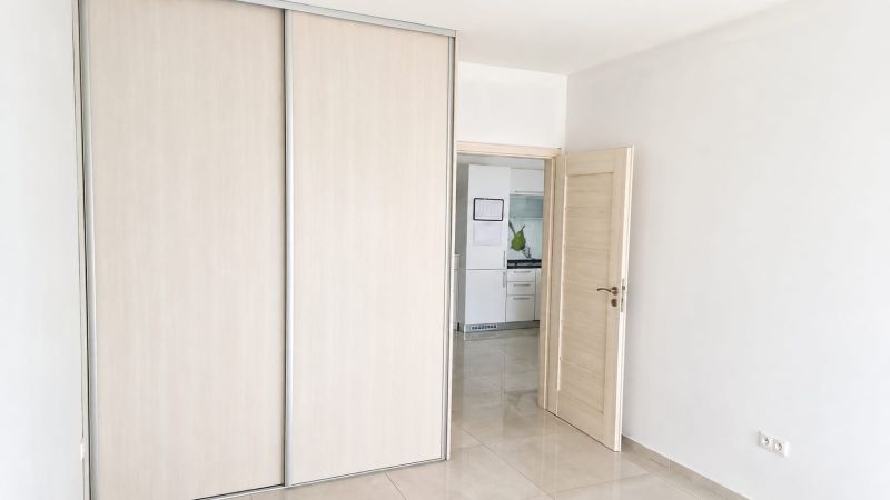 A double-wing wardrobe with sliding doors and open doors to the kitchen in a 2-room apartment.