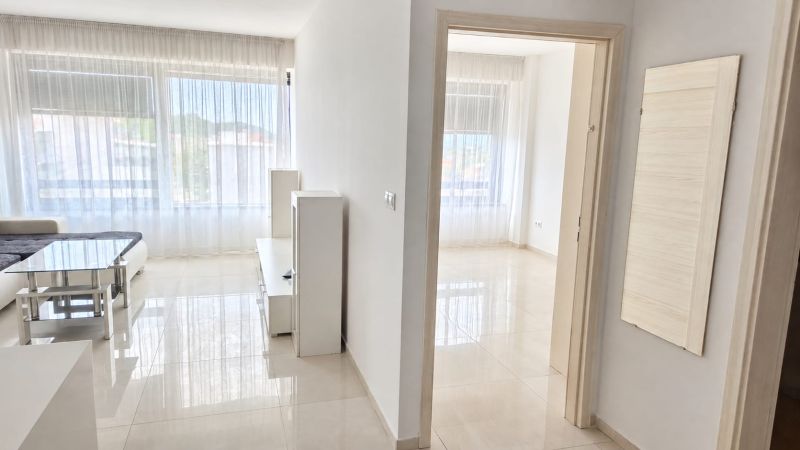 Large windows with white curtains in a bright 2-room apartment with ceramic tiles.