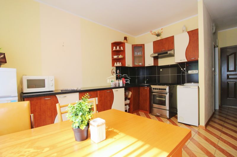 A kitchen in a studio apartment with a wooden decor floor and a dining table.