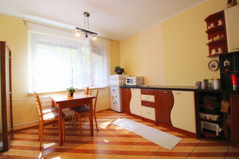 A kitchen in a studio apartment with a dining table and a wood-patterned floor.