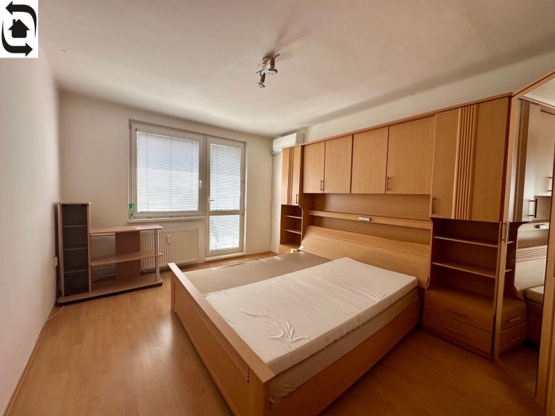 Bedroom in a 4-room apartment with a bed and wardrobes, floor with wood decor.