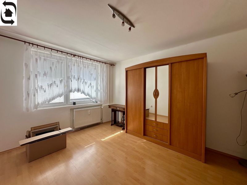 A room with a wooden decor floor, wardrobes, and a large window in a 4-room apartment.