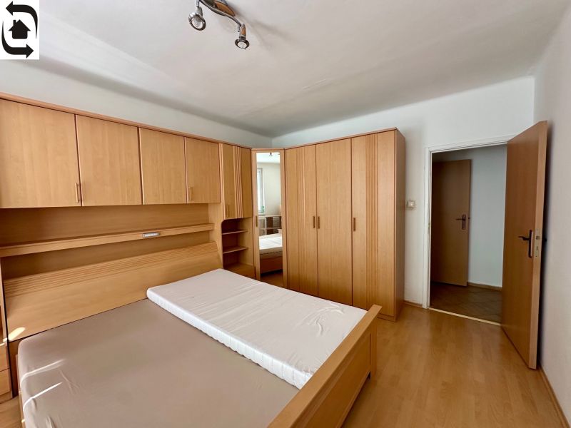 A bedroom with a bed and wardrobes in a 4-room apartment with a wooden decor floor.