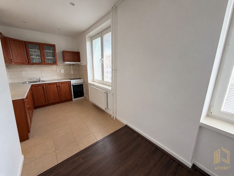 A kitchen in a 2-room apartment with wooden decor and tiled flooring.