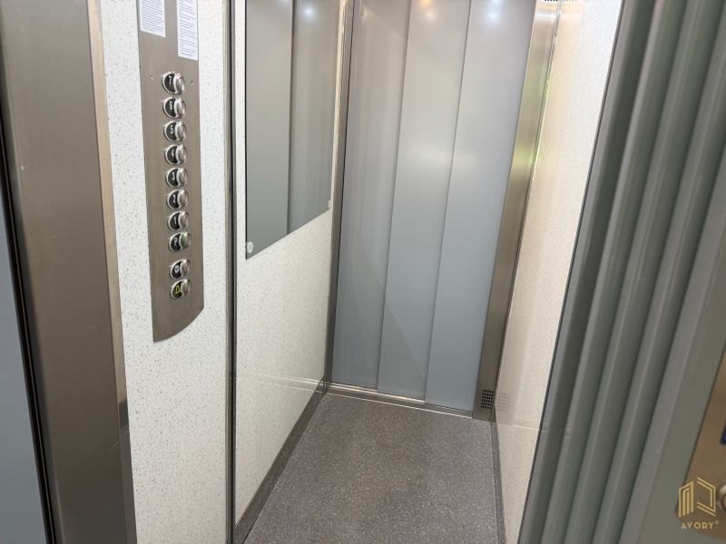 The interior of an elevator with buttons and a mirror in a 2-room apartment.