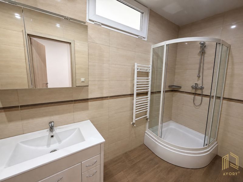 Bathroom with a shower and a mirror with a wooden decor floor in a 2-room apartment.