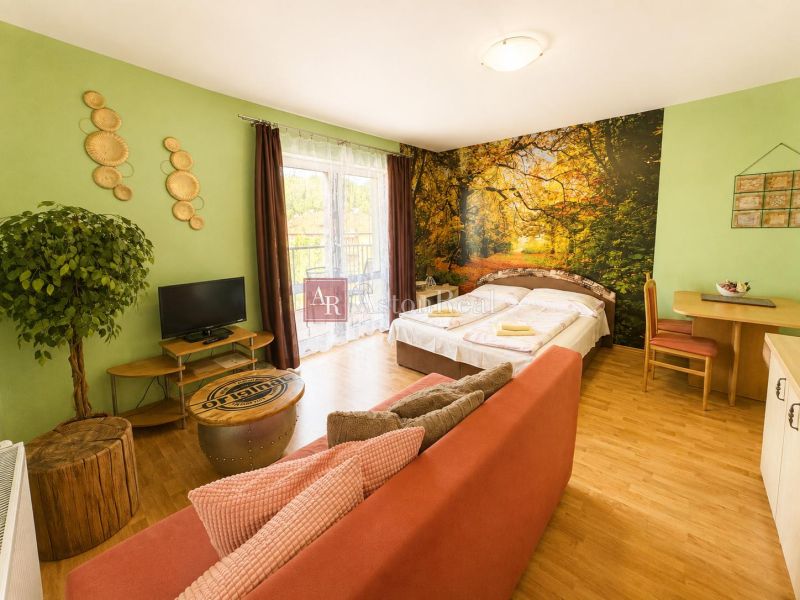 A room with a bed, sofa, and television, with a wooden decor floor.